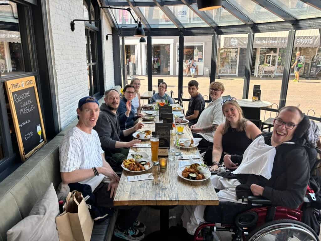 Eine große Gruppe sitzt gemeinsam an einem langen Holztisch in einem Restaurant.