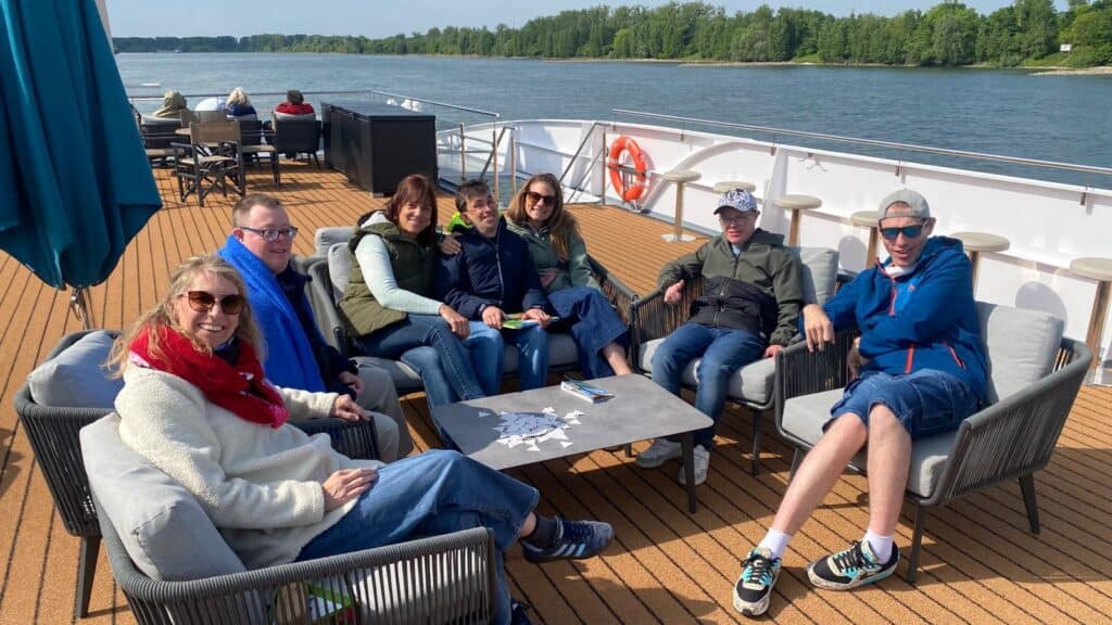 Eine Gruppe von Personen sitzt auf dem Sonnendeck eines Schiffs.