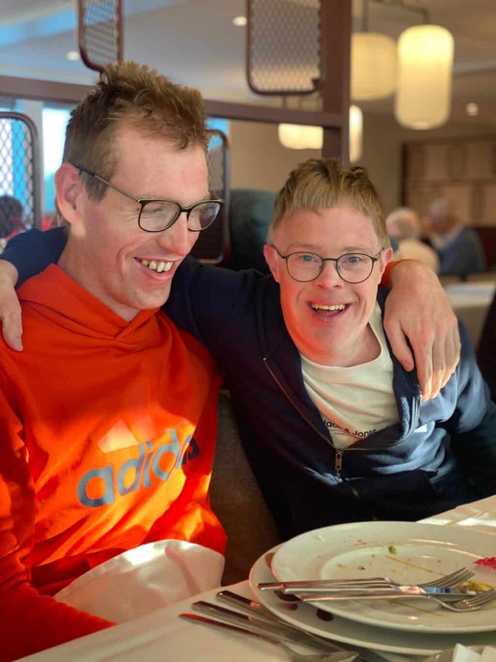 Zwei Männer sitzen im Restaurant und lachen herzlich zusammen.