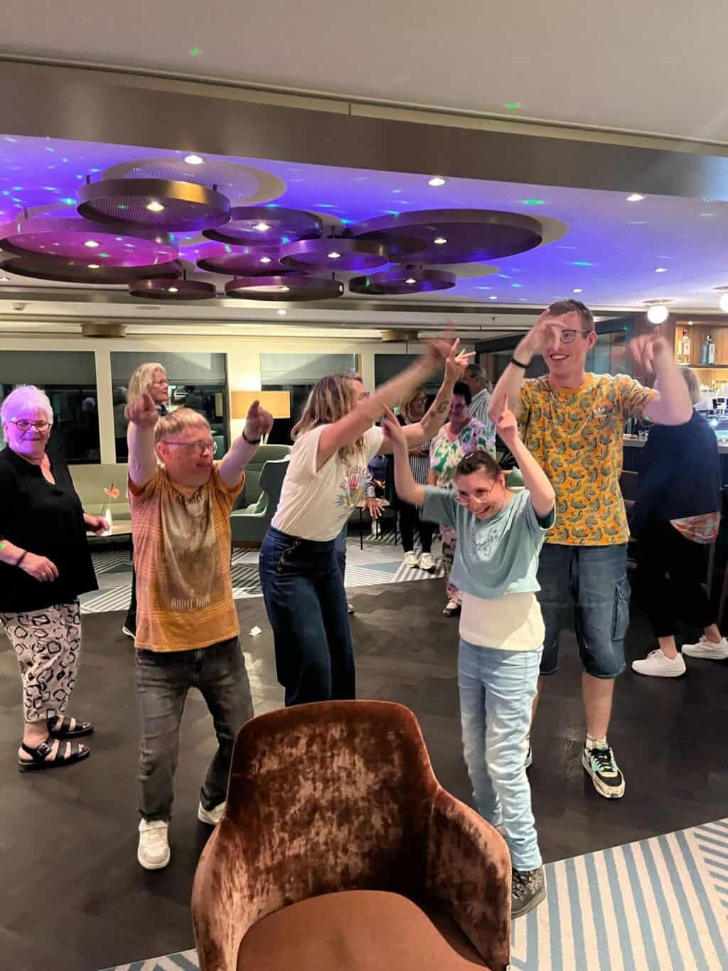 Eine Gruppe tanzt gemeinsam unter bunter Beleuchtung.