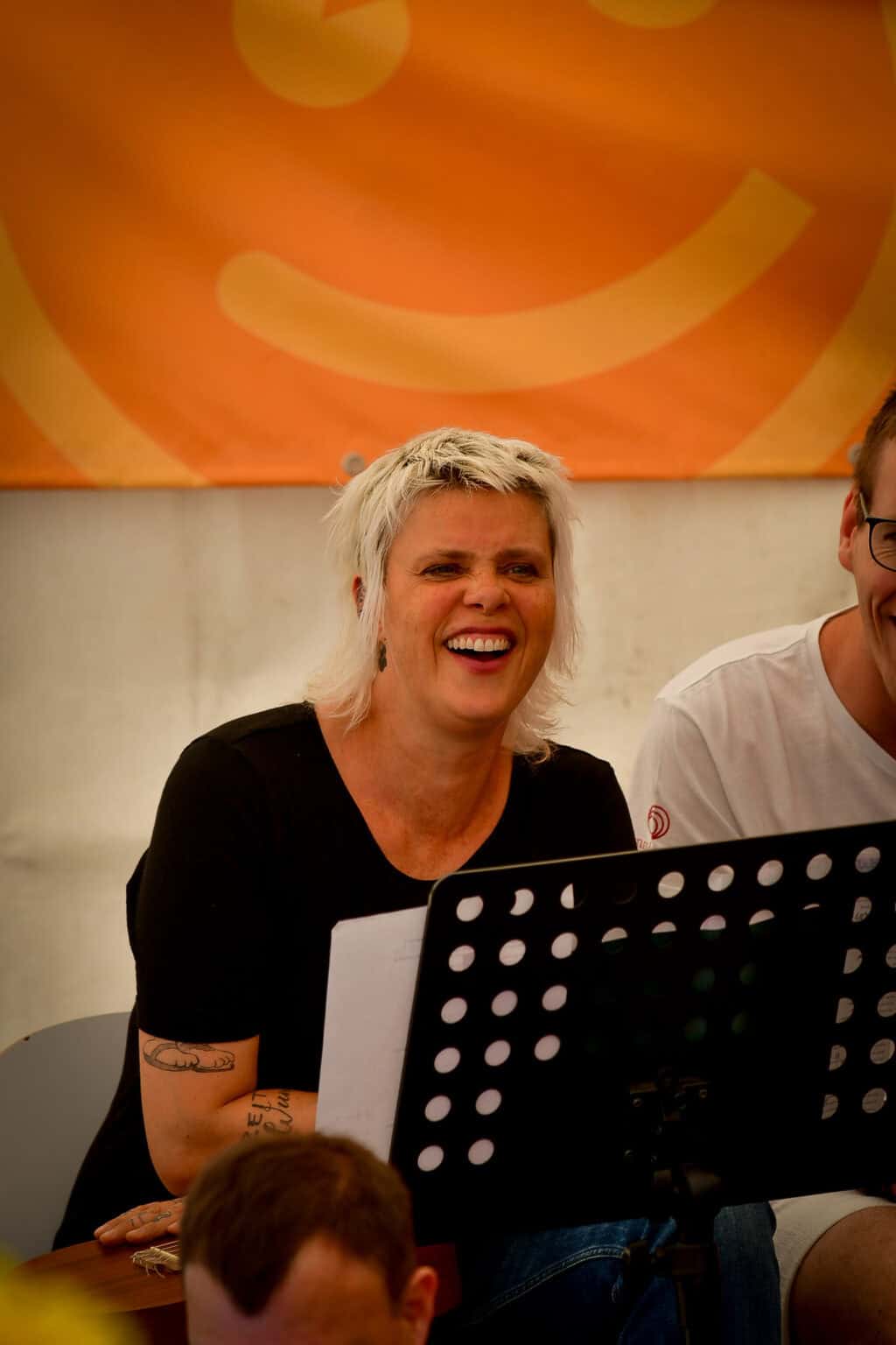 Eine Teilnehmerin der Musikgruppe Atemlos sitzt auf der Bühne und lacht herzlich.